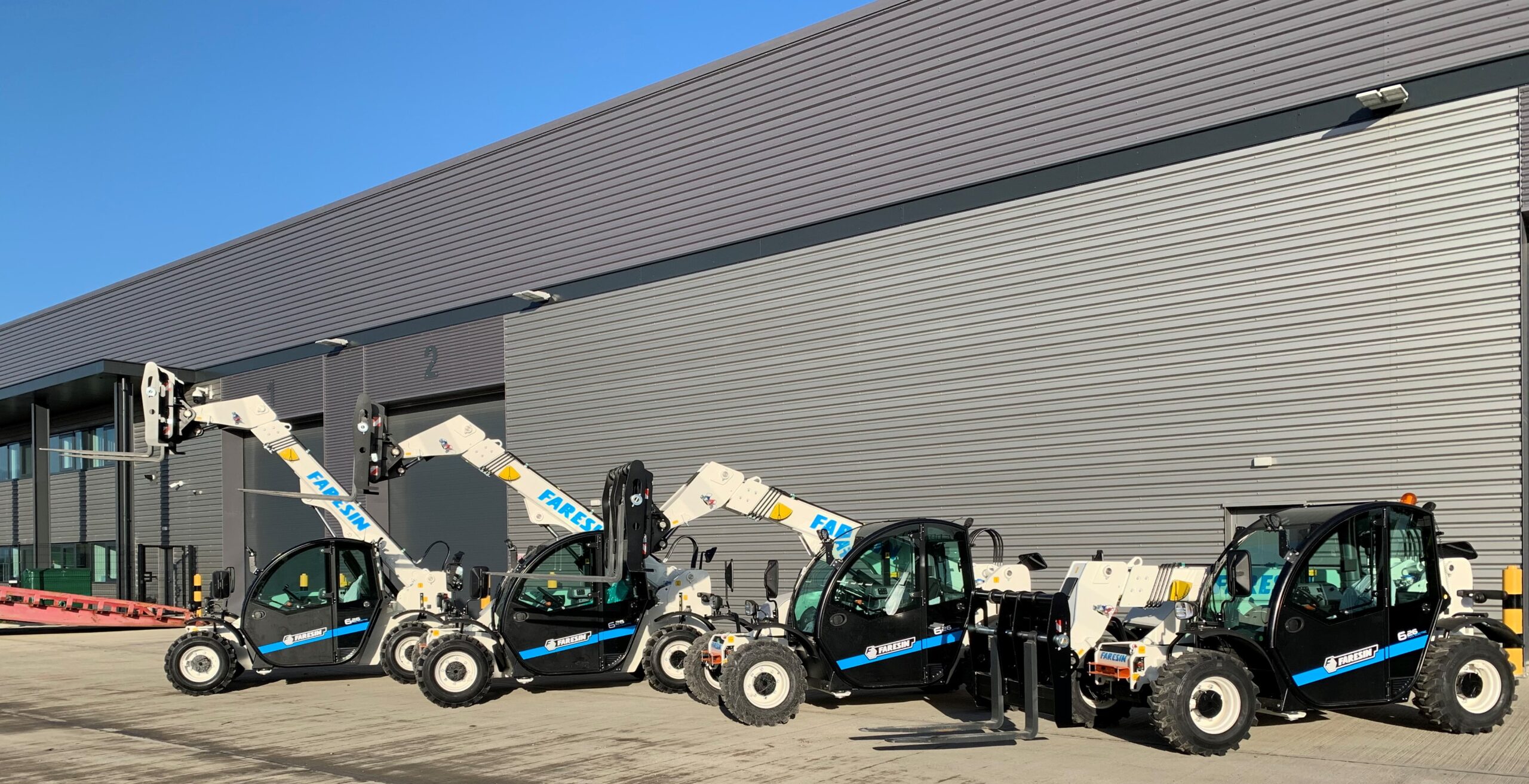 An image of 4 Electric Telehandlers in front of a construction depot